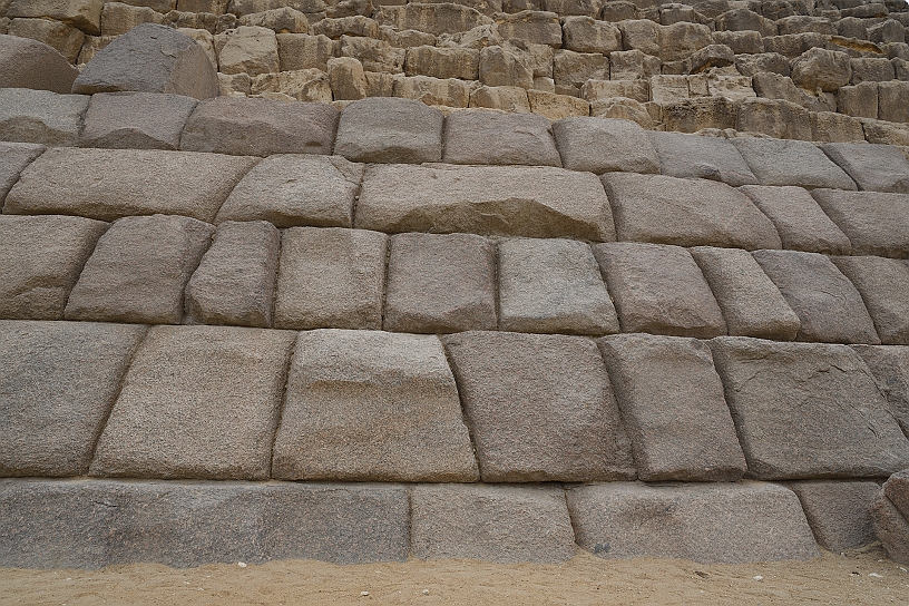 64 MAK_6822.jpg - I blocchi alla base della piramide di Micerino sono di granito rosa di Assuan, molto più grandi anche di quella di Chefren, ma le facce della piramide hanno superfici imperfette e le pietre sembrano sistemate in fretta, probabilmente per la prematura scomparsa del faraone.